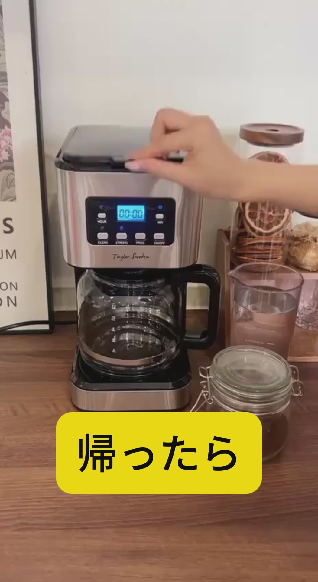 プログラム式コーヒーメーカーを実際に使っている様子の縦型動画。水と粉をセットし、ボタンを押してコーヒーを抽出し、ガラスポットからカップに注ぐまでの流れが映ります。音声はありません。
